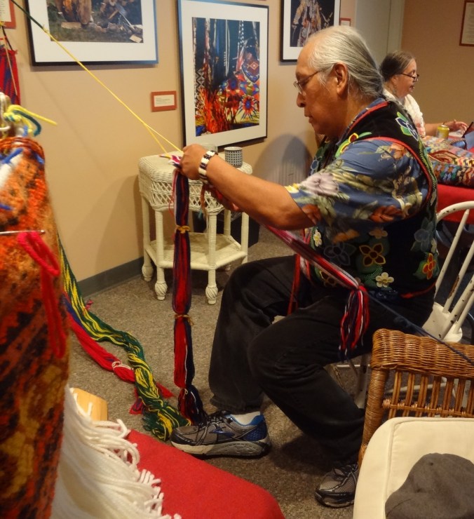 Dennis White demonstrates finger weaving in the LaPointe Museum.